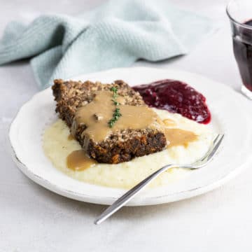 veggie meatloaf (nut loaf) with mashed potatoes, gravy, and cranberry sauce on a plate