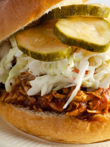 instant pot bbq chicken on a roll with coleslaw and pickles