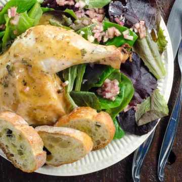 chicken with rosemary and thyme on a plate with baguette croutons and salad