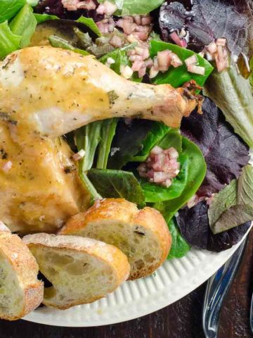 chicken with rosemary and thyme on a plate with baguette croutons and salad