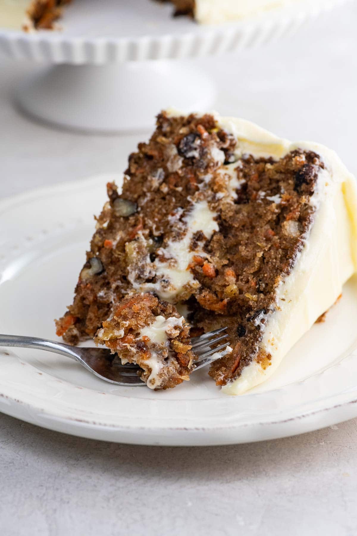 a slice of King Arthur carrot cake with not too sweet cream cheese frosting on a plate