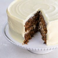 old fashioned carrot cake with pineapple on a cake stand, with one slice cut out