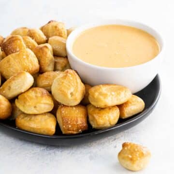 homemade soft pretzel bites on a black plate and pretzel cheese dip in a white bowl