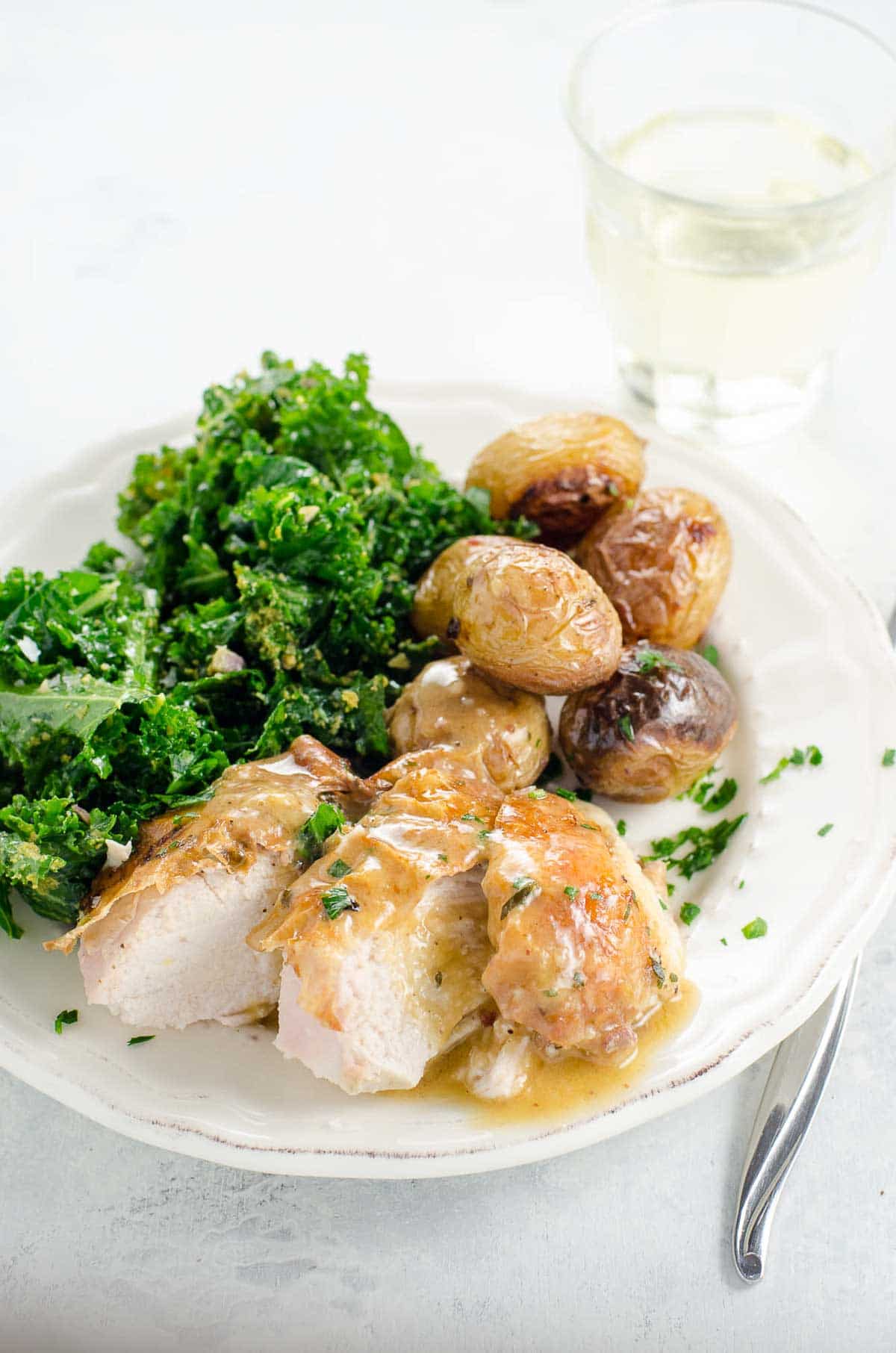 roast chicken and potatoes with kale salad on a plate