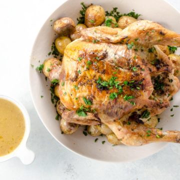 Roast chicken and potatoes in a serving bowl with gravy