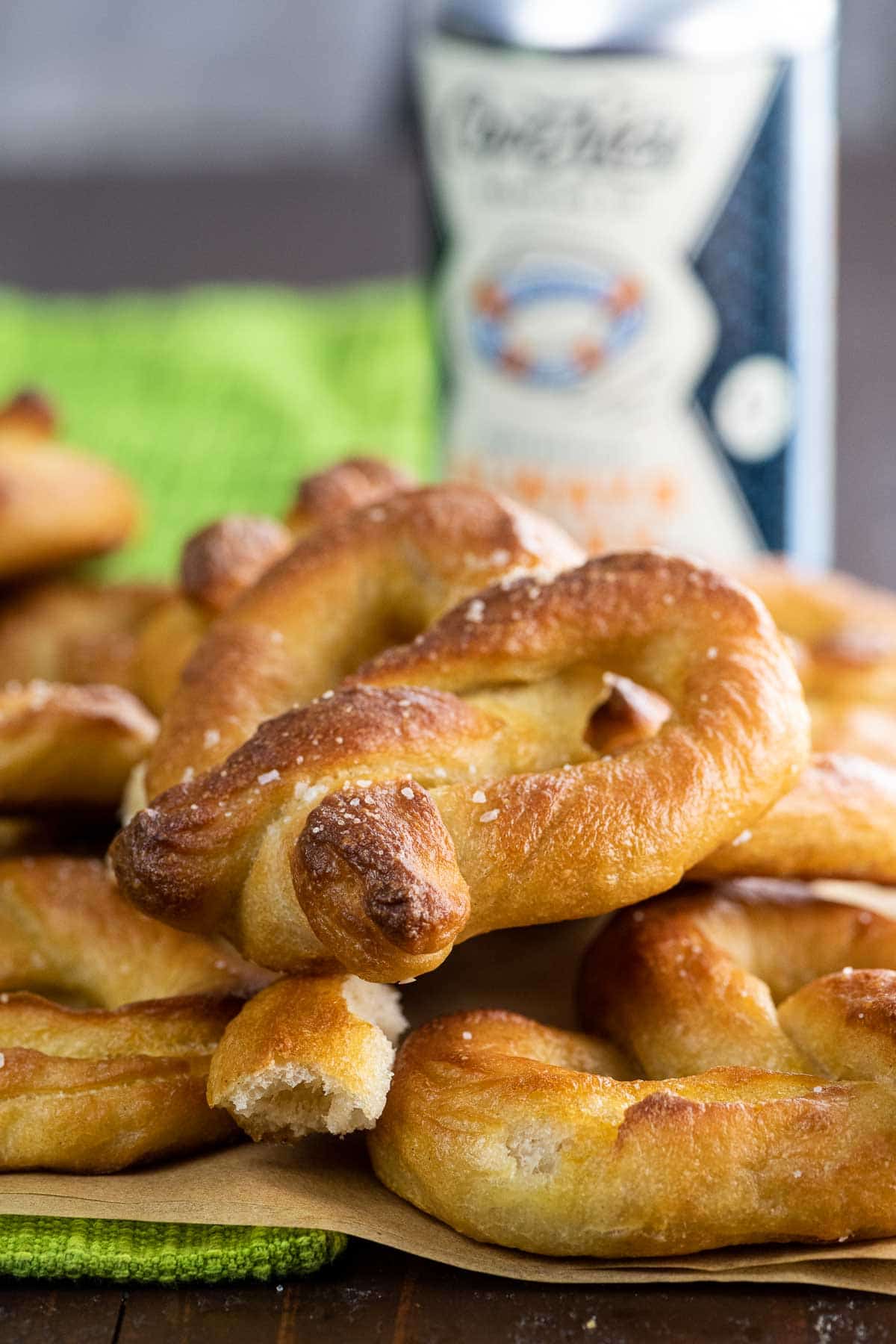 a big pile of vegan soft pretzels on a table with mustard and beer