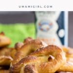 a big pile of vegan soft pretzels on a table with mustard and beer