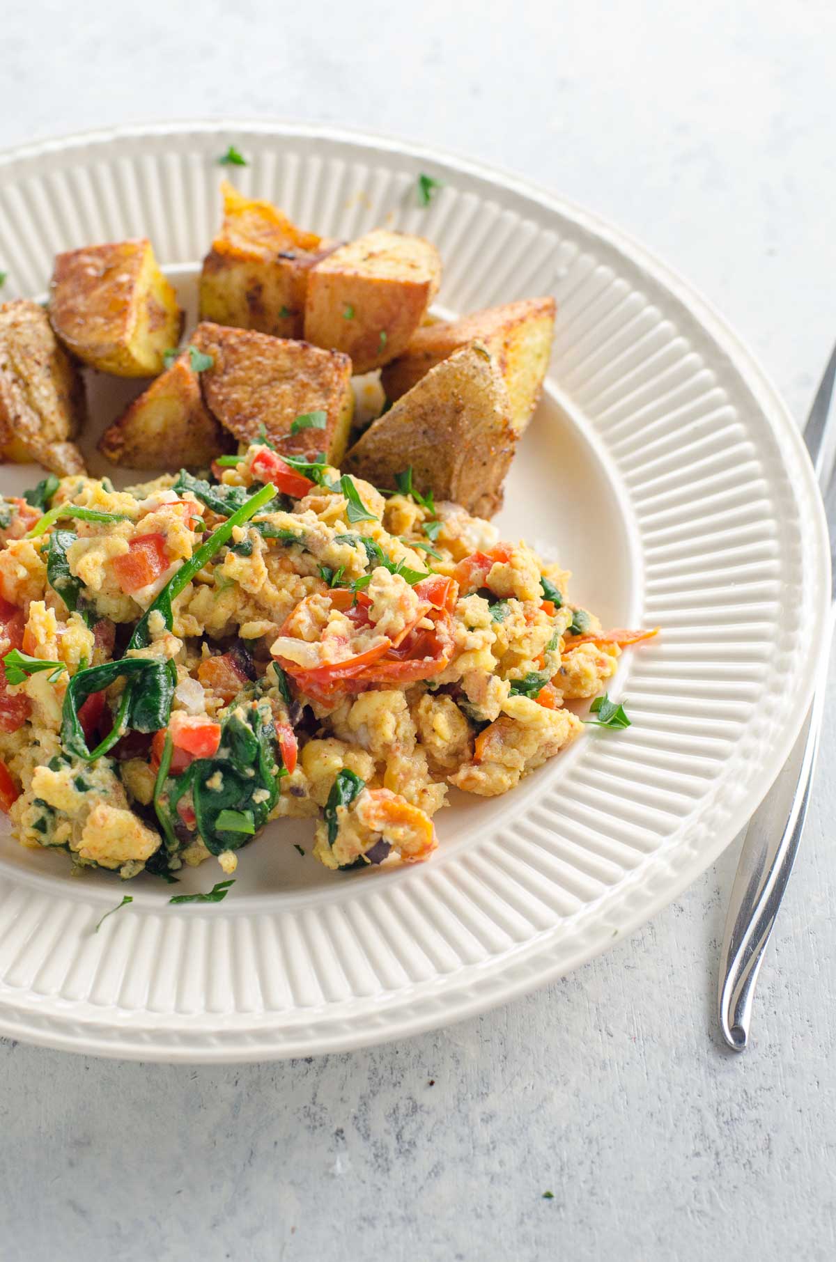 veggie breakfast scramble and roasted potatoes on a plate with a fork