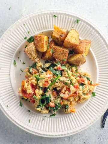 veggie breakfast scramble and roasted potatoes on a plate with a fork