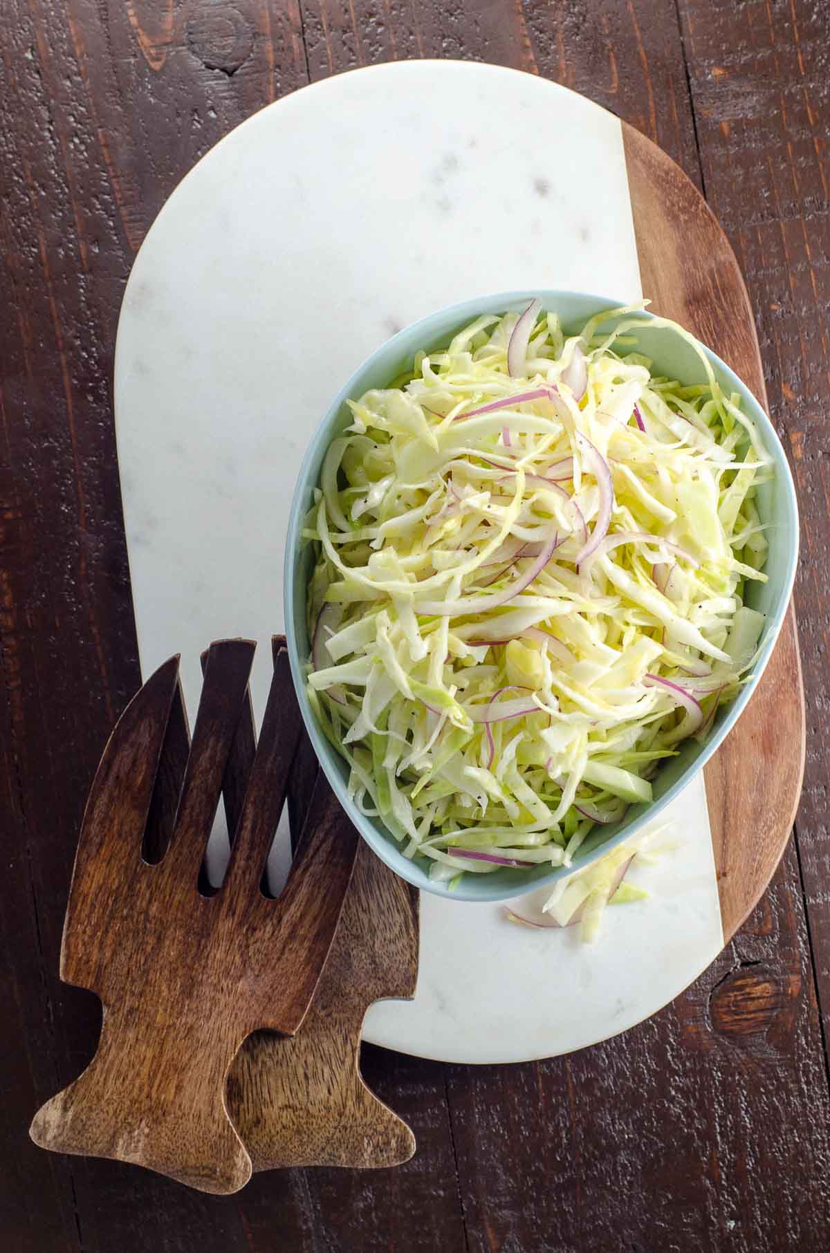 alice waters vegan coleslaw recipe with no mayo in a bowl with salad hands