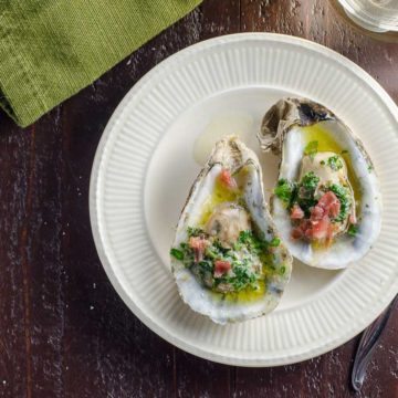 baked oysters with shallot herb butter and prosciutto on a plate
