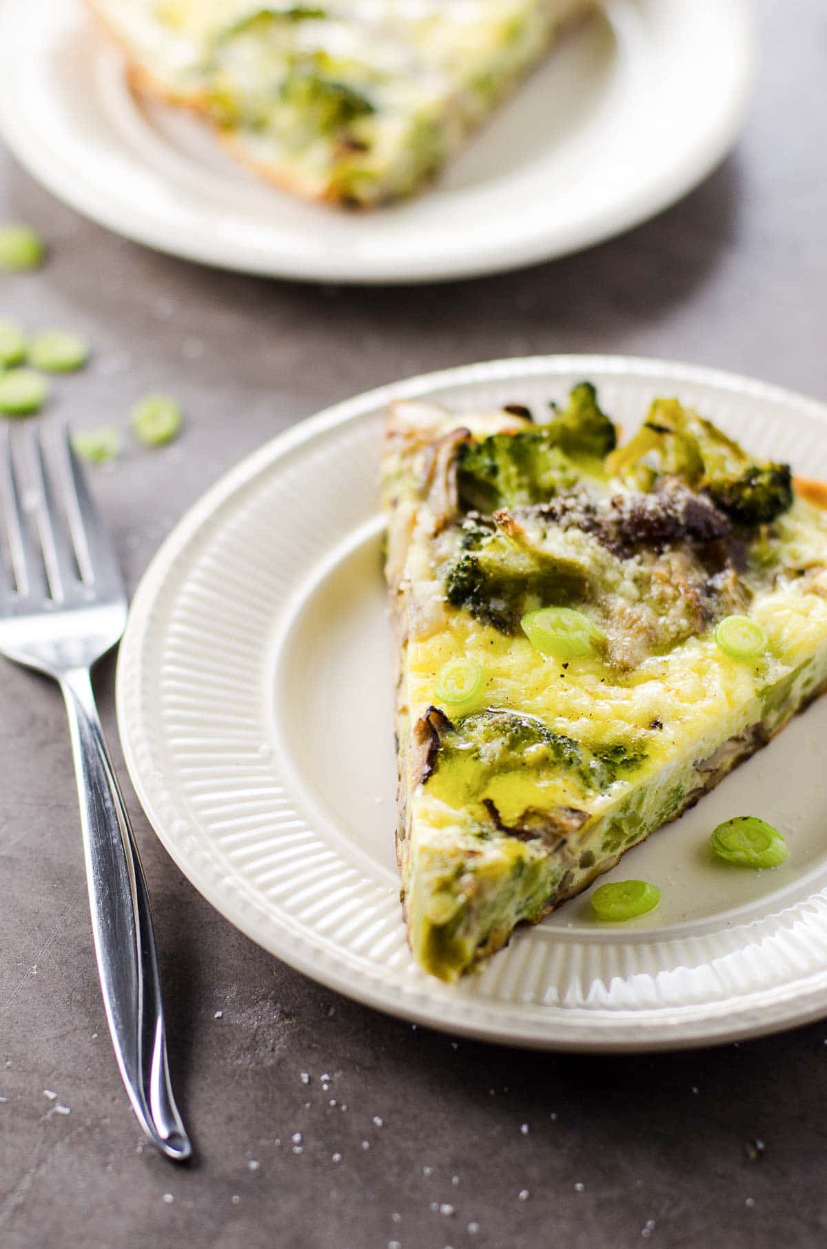 a slice of broccoli mushroom frittata on a plate with a fork