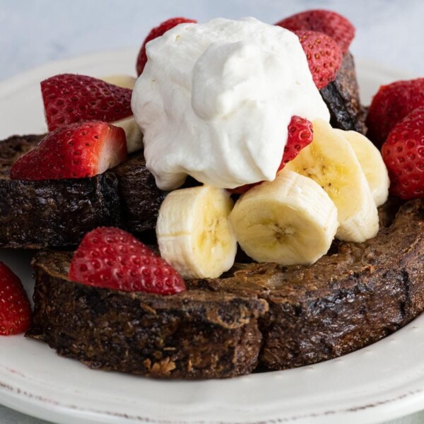 chocolate sourdough french toast with fresh fruit and whipped cream on a plate