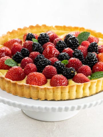 lemon curd tart with shortbread crust and berries on a cake stand