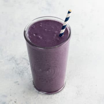 liquid love purple maca smoothie with a blue and white straw in a glass
