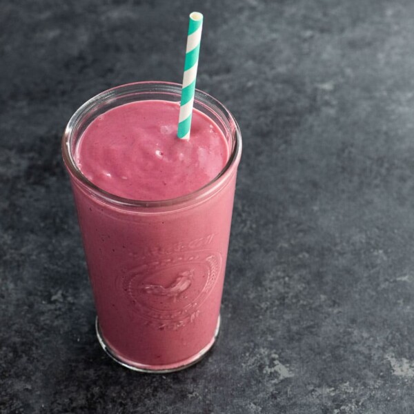 a peanut butter and jelly protein shake in a glass with a straw