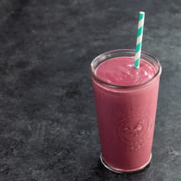 a peanut butter and jelly protein shake in a glass with a straw