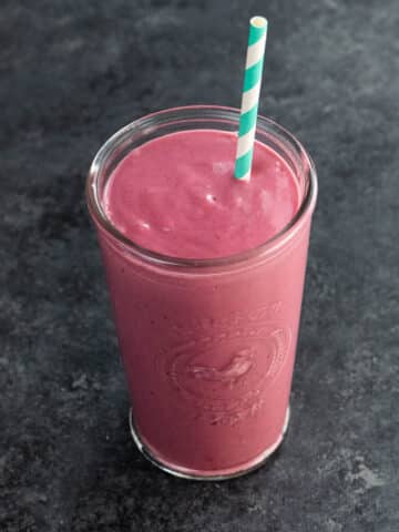 a peanut butter and jelly protein shake in a glass with a straw