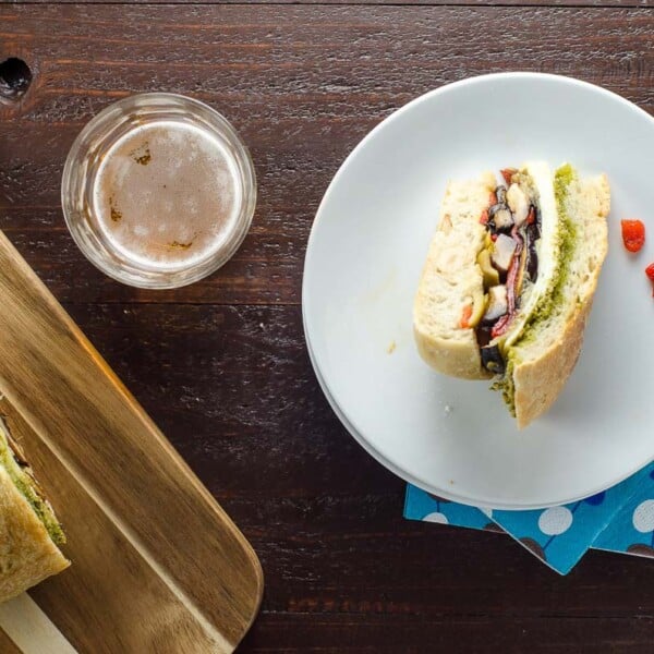 a slice of vegetarian muffaletta on a plate and a glass of beer