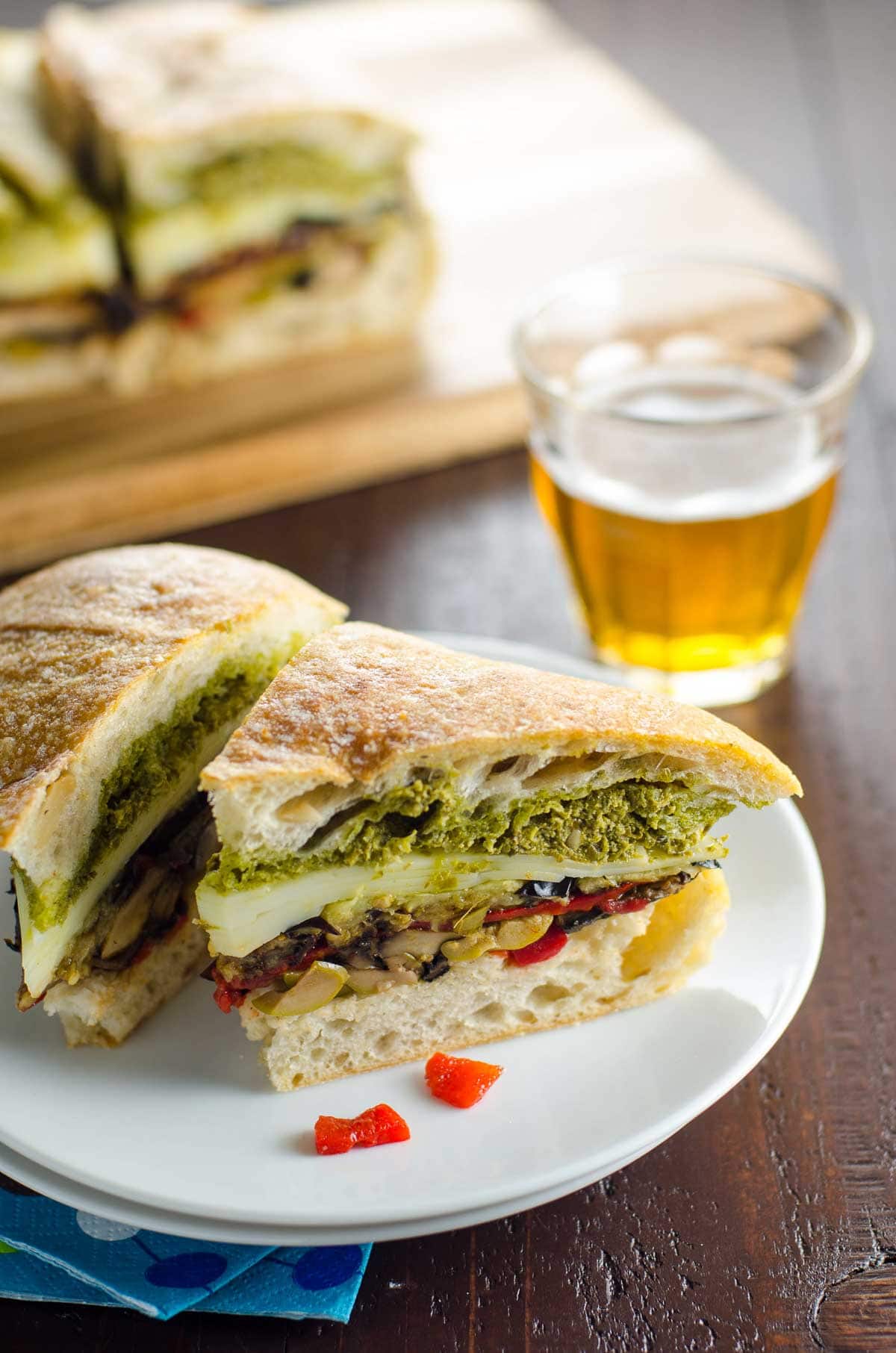 slices of vegetarian muffaletta on a plate and a glass of beer