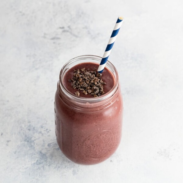 a cherry smoothie with chocolate in a mason jar with a blue and white paper straw