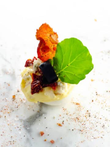 a cobb salad deviled egg on a marble background