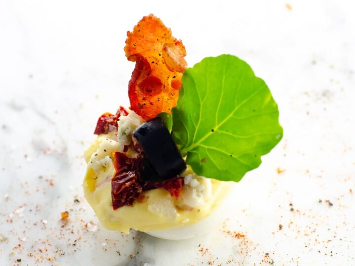 a cobb salad deviled egg on a marble background