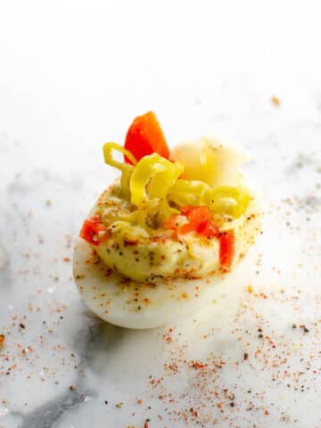 a giardiniera deviled egg on a marble background