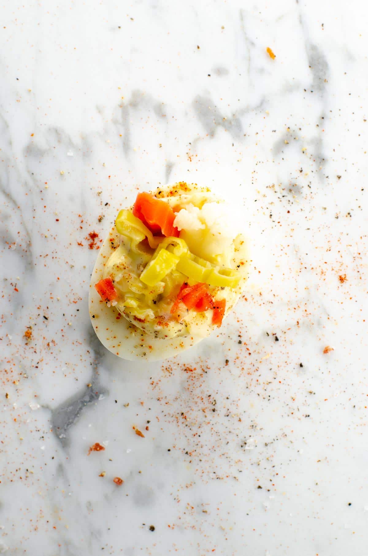 a giardiniera deviled egg on a marble background