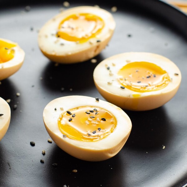 ramen eggs on a black plate with chopsticks