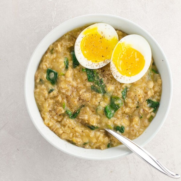 savory oats recipe with spinach and an egg in a bowl with a spoon