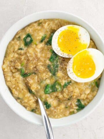 savory oats recipe with spinach and an egg in a bowl with a spoon