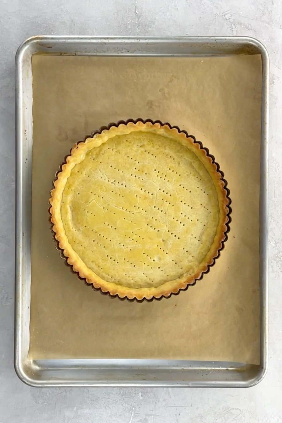 a blind baked shortbread tart crust on a baking sheet