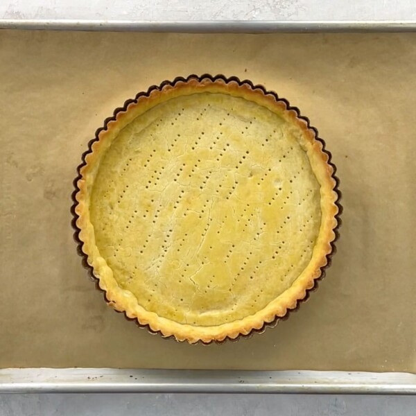 a blind baked shortbread tart crust on a baking sheet