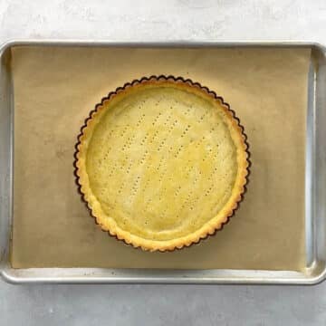 a blind baked shortbread tart crust on a baking sheet