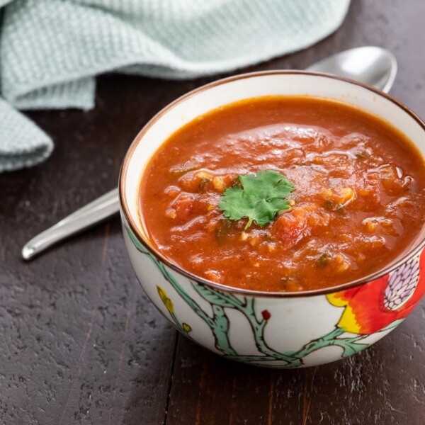 spiced tomato soup with red lentils in a bowl with a spoon and napkin