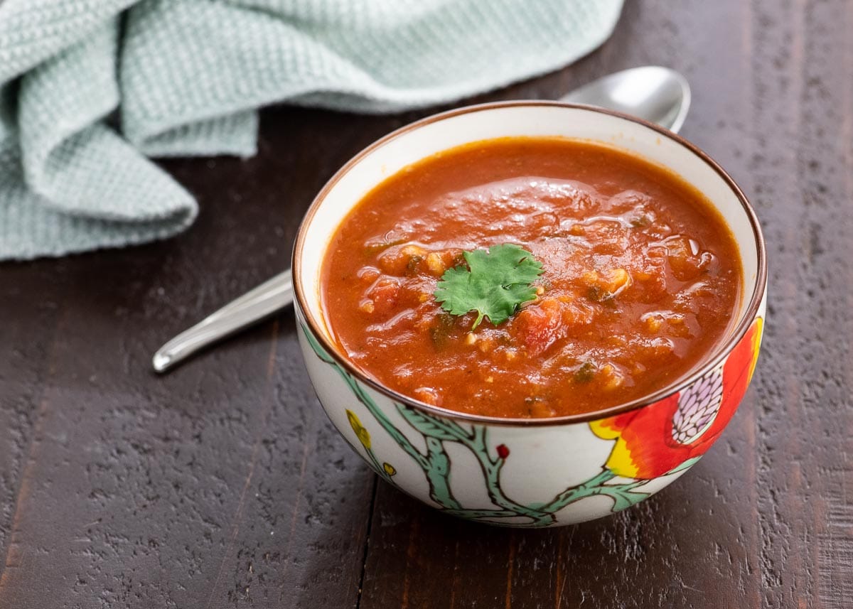 spiced tomato soup with red lentils in a bowl with a spoon and napkin