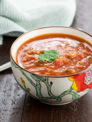 spiced tomato soup with red lentils in a bowl with a spoon and napkin