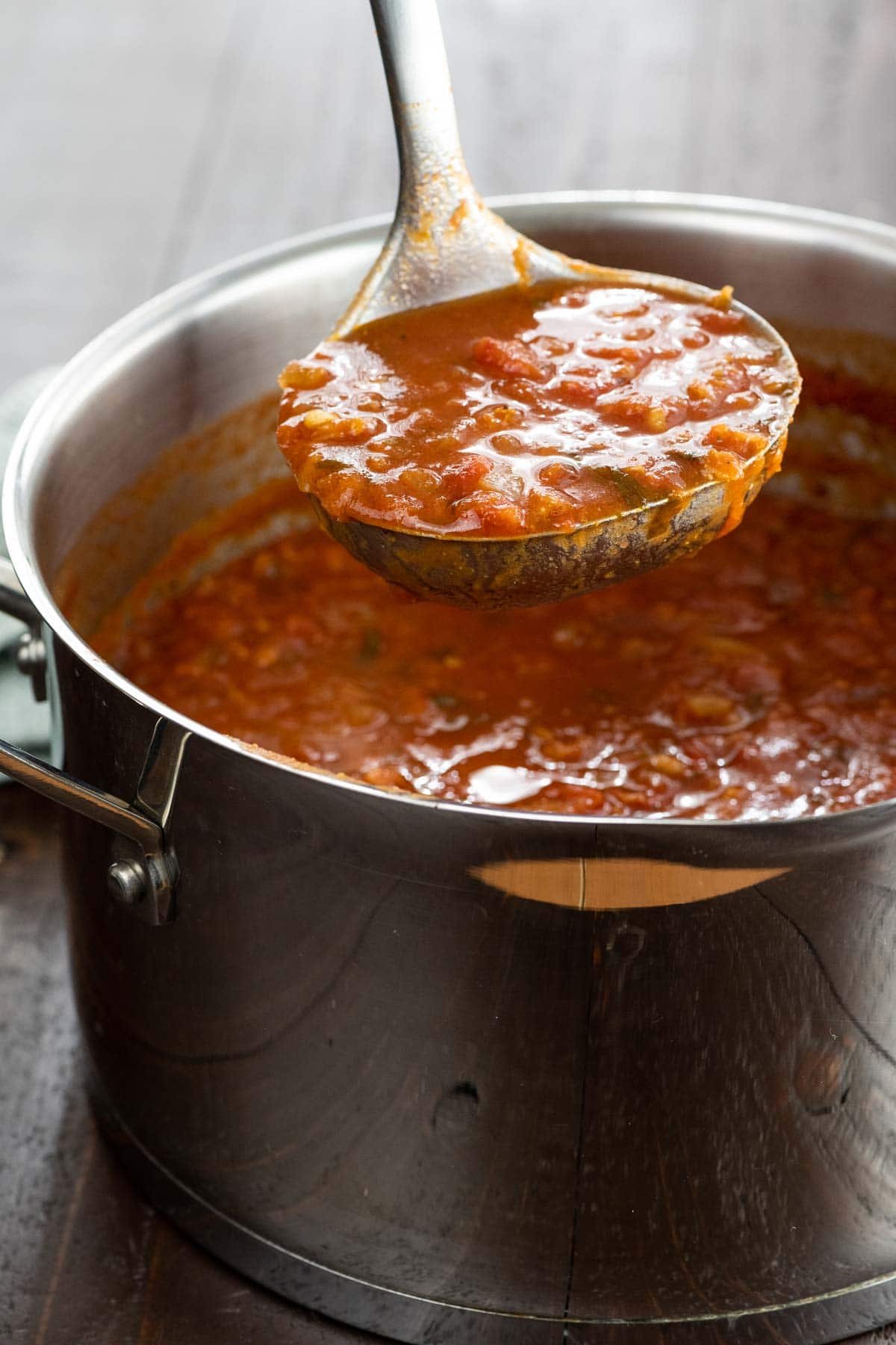 spiced tomato soup with red lentils in a pot with a ladle