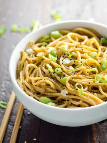 spicy sesame garlic noodles in a white bowl with chopsticks