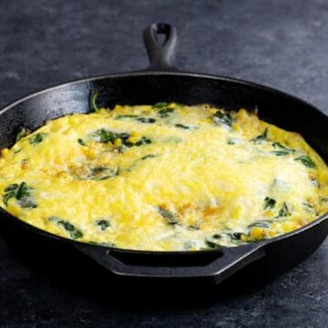 a spinach cheddar corn frittata in a cast iron pan
