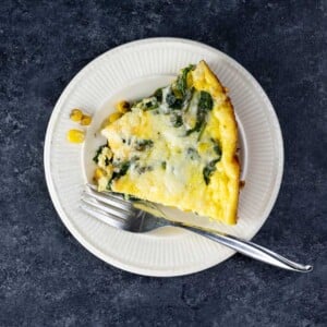 a slice of spinach cheddar corn frittata on a plate with a fork