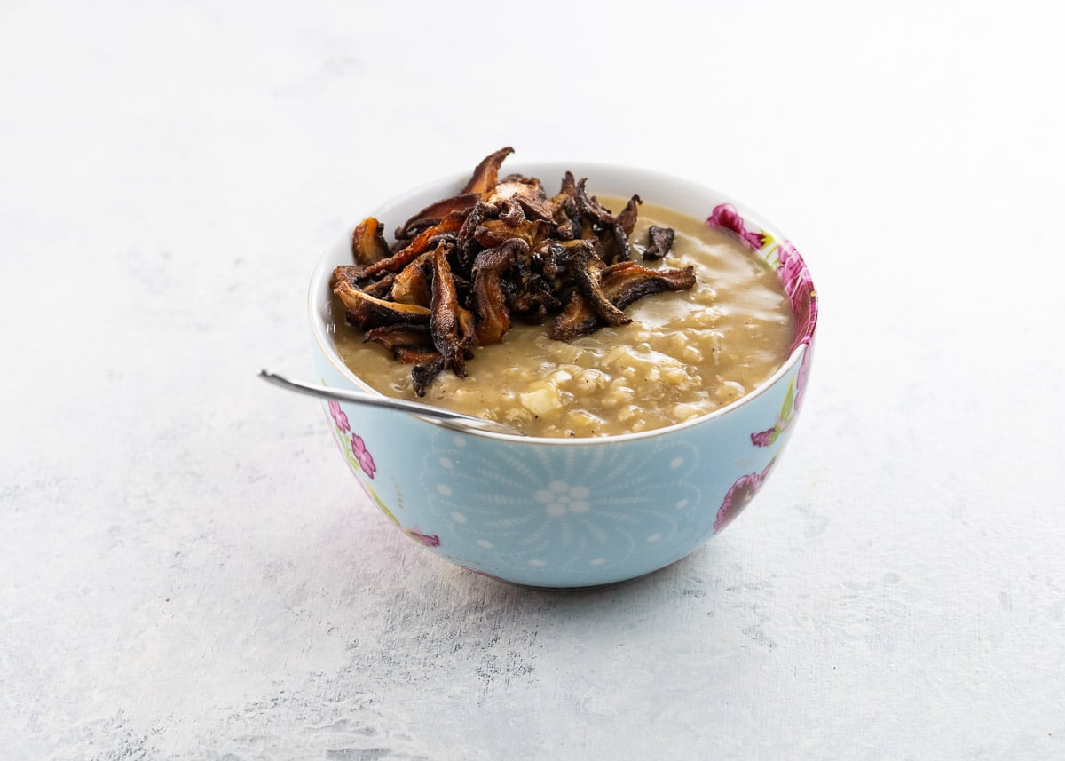 vegan savory oatmeal with shiitake bacon in a bow with a spoon