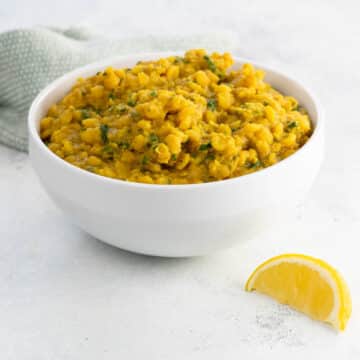 yellow split pea dahl in a bowl with a lemon wedge and a napkin