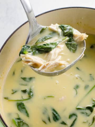 avgolemono soup (greek lemon chicken soup) with orzo and spinach in a pot with a ladle
