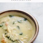 a bowl of avgolemono soup with orzo and spinach, and a spoon