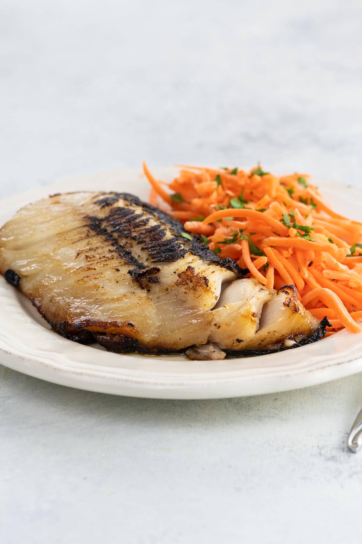 Nobu miso black cod on a plate with shredded carrots and parsley