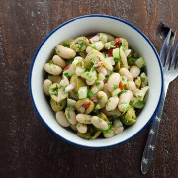 white bean salad with olives in a bowl with a fork