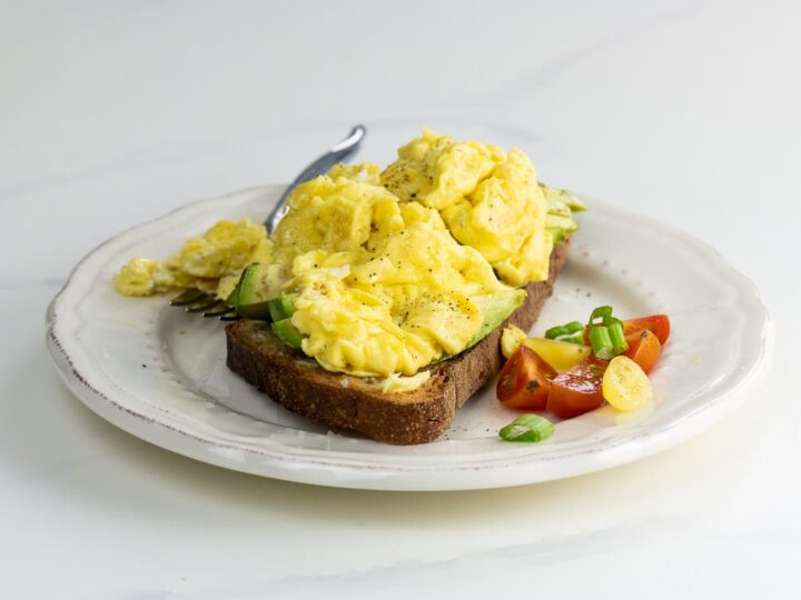 avocado toast with scrambled egg on a plate with a fork