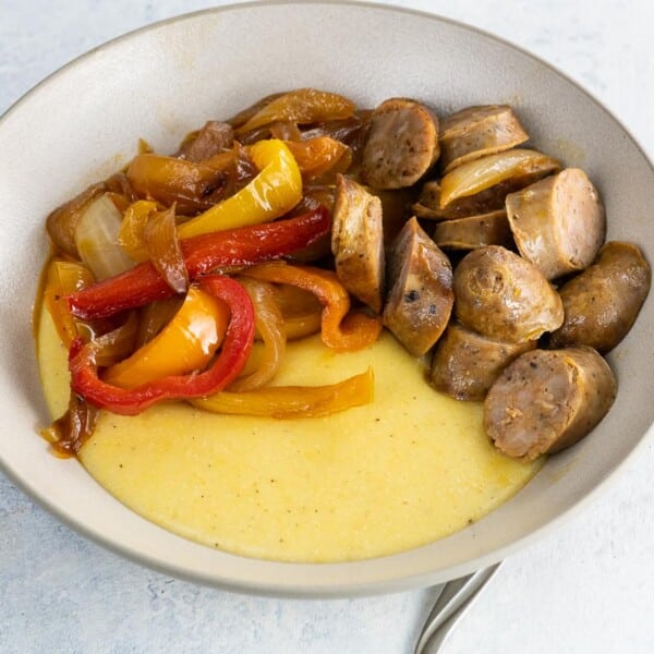 cheddar polenta in a bowl with sausage and peppers